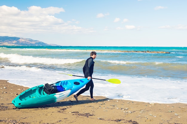 man carrying kayak at sea beach