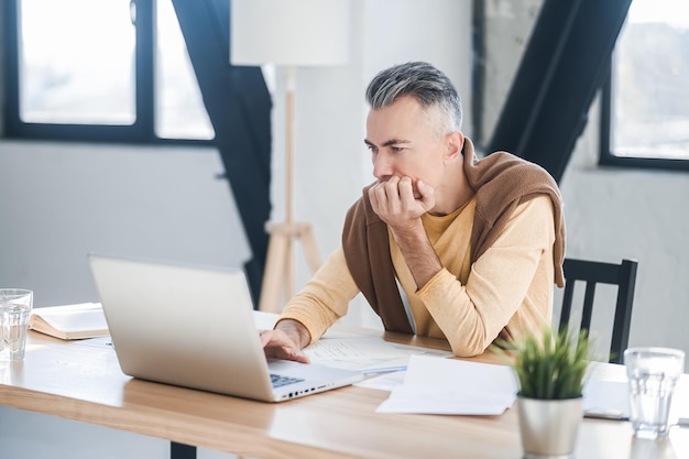 A man in casual clothes working in the office and looking involved