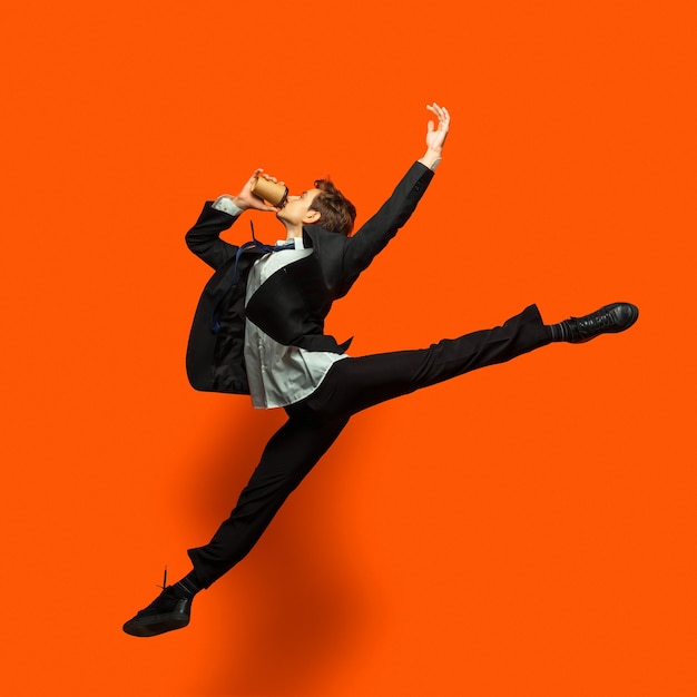 Man in casual office style clothes jumping isolated on studio background