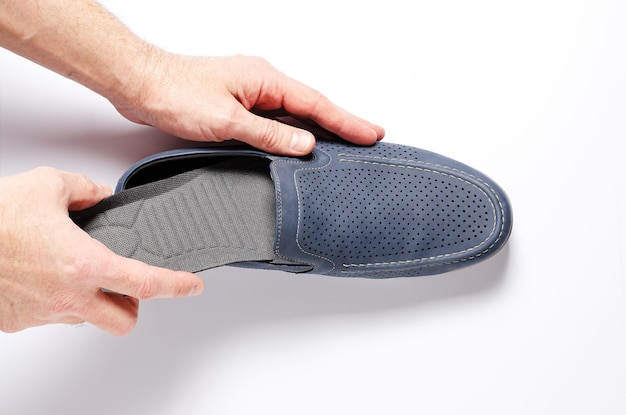 A man changes the insole in his shoes White background closeup