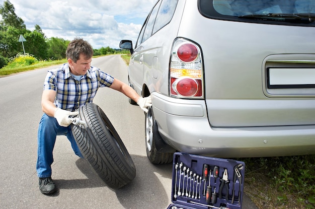 Man changing wheel of car