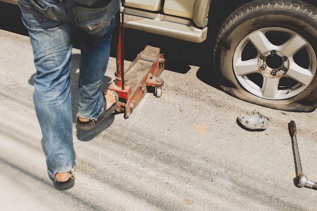 A man changing the wheel at the side of the road