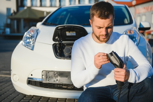 Man charges an electric car at the charging station