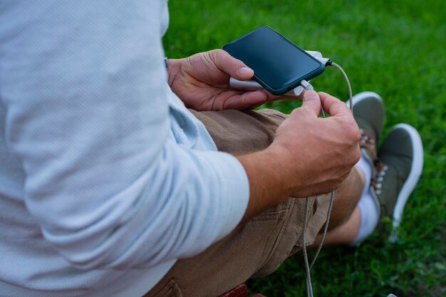 Man charges a smartphone with a power bank in hand. Portable charger for charging gadgets.