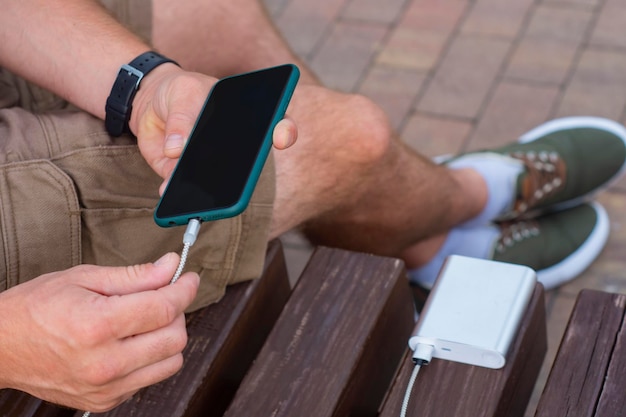 Man charges a smartphone with a power bank in hand Portable charger for charging gadgets