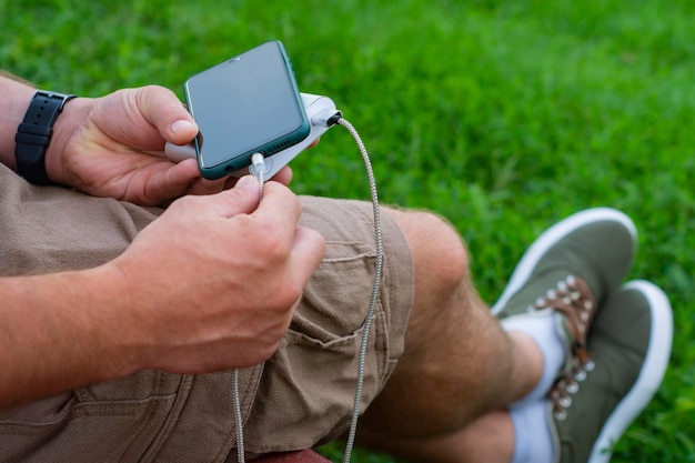 Man charges a smartphone with a power bank in hand Portable charger for charging gadgets