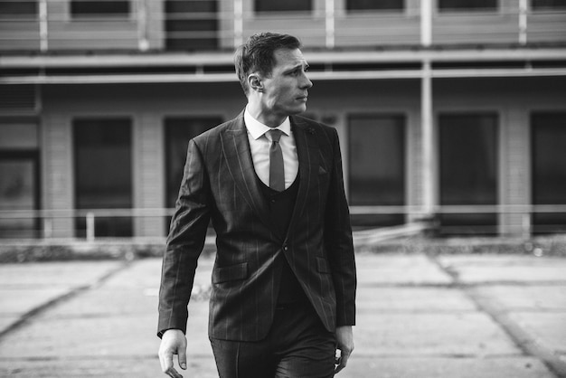 A man in a checkered suit poses on the street to advertise men's clothing.