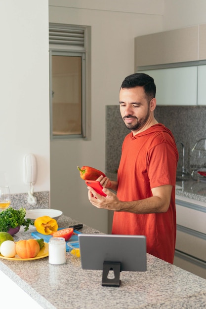 Man checking his cell phone while cooking at home