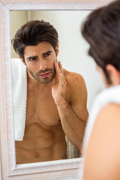 Man checking his skin in bathroom