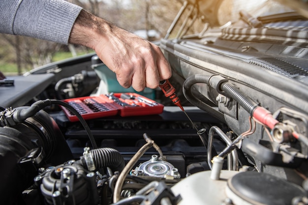 A man checks the oil of a car under the hood