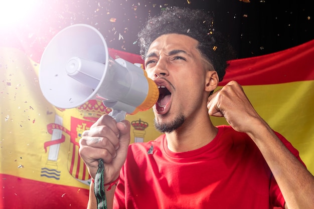 Man cheering and speaking through megaphone with spanish flag