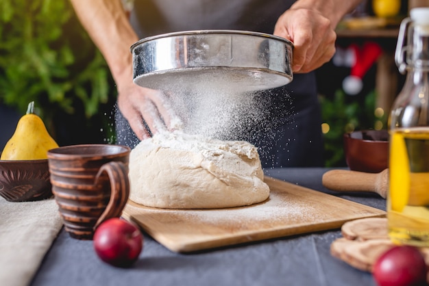 Man chef in a black apron kneads the dough with his hands for Christmas baking