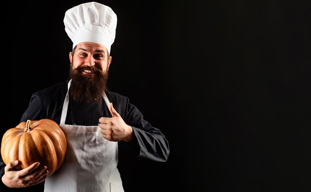 Man in chef uniform with pumpkin showing thumb up useful vegetables autumn harvest cooking recipe