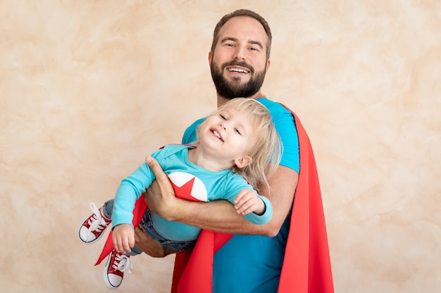 Man and child super hero at home. Superhero father and son having fun together.