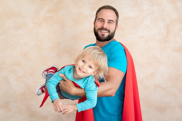 Man and child super hero at home. Superhero father and son having fun together.