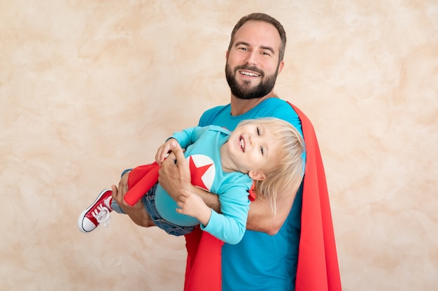 Man and child super hero at home. Superhero father and son having fun together.