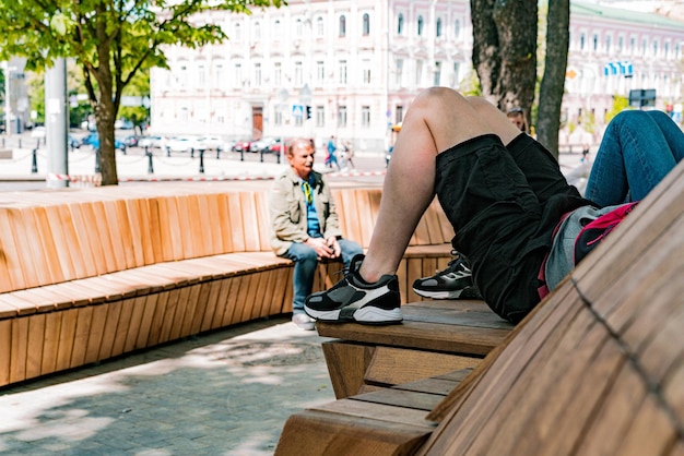 Man chilling on a long wooden bench in the city square Comfortable Geometry Wooden Brown Sunny Steps Gardening Perspective Peaceful Material Walk Sidewalk ScenicBig Plank Object Road