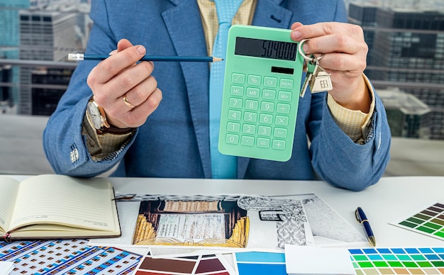 Man chooses colors for room design drawing modern apartments with color swatch and laptop on creative desk in office The designer's hands pick up the collars The designer is a man