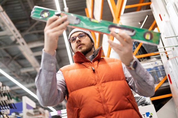 A man chooses a construction bubble level in a building materials and tool store