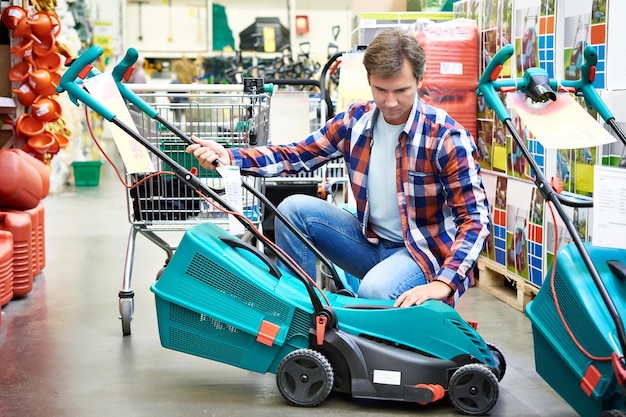 Man chooses lawn mower in store