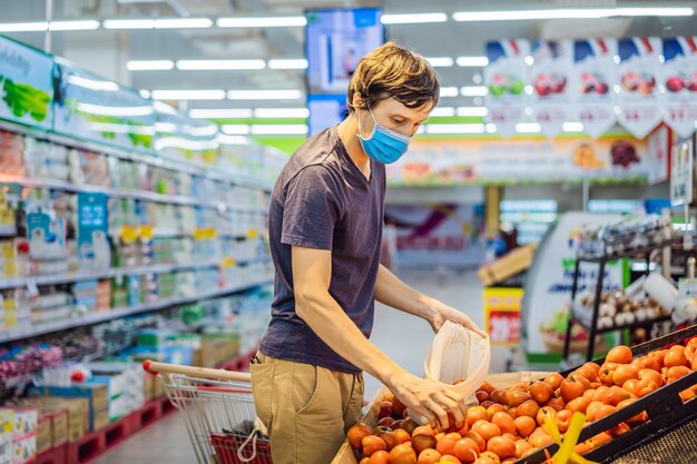 Man chooses tomatoes in a supermarket without using a plastic bag reusable bag for buying vegetables