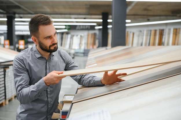 Photo man choosing laminate samples in hardware store