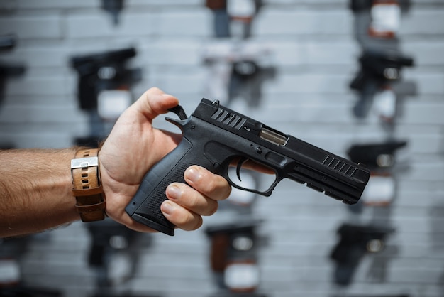 Man choosing new handgun at showcase in gun shop