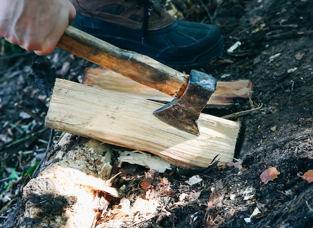 Man chops wood outdoors. Tourist in the wood with an axe.