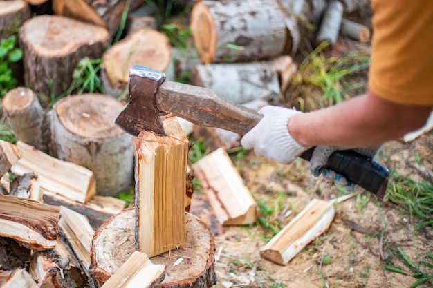 A man chops wood with a large ax procurement of fuel for the winter for heating housing selective