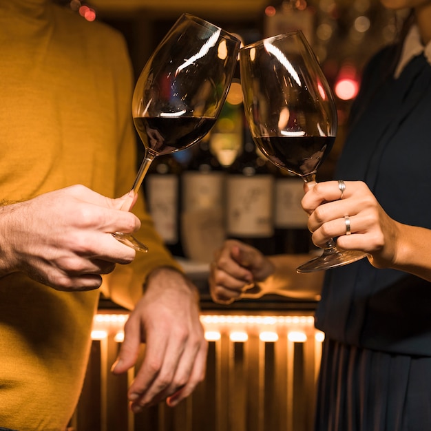 Man clanging glasses of drink with woman