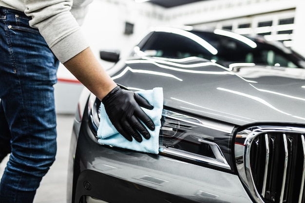 A man cleaning car with microfiber cloth, car detailing (or valeting) concept. Selective focus.