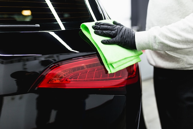 A man cleaning car with microfiber cloth, car detailing (or valeting) concept. Selective focus.