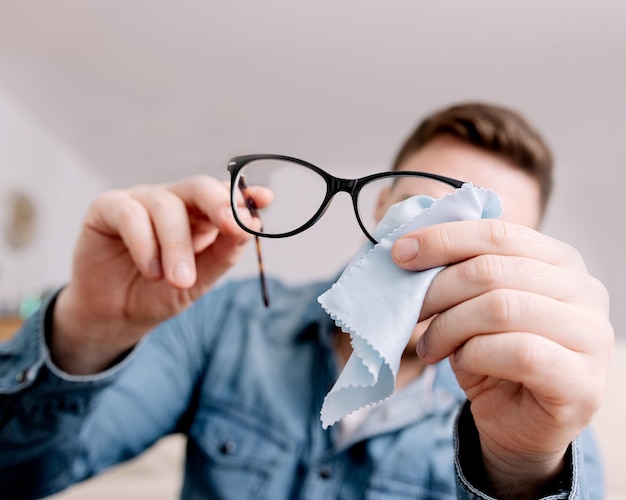 Man Cleaning Eyeglasses with Cloth Focused on Maintenance and Care