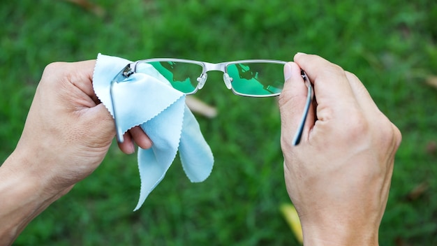 Photo man cleaning the glasses with microfiber fabric.