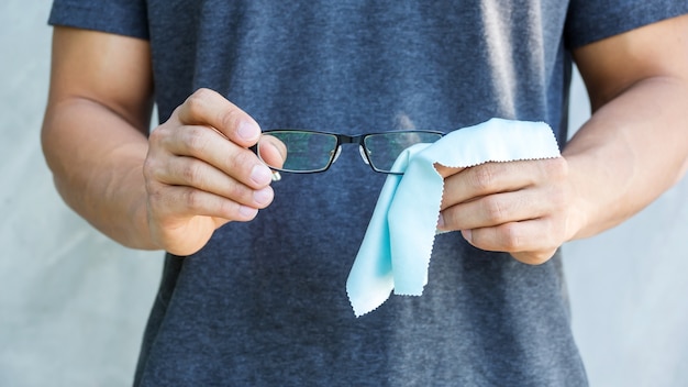 Photo man cleaning the glasses with microfiber fabric.