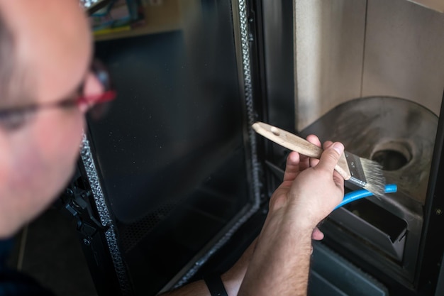 Man cleaning pellet stove with a vacuum cleaner