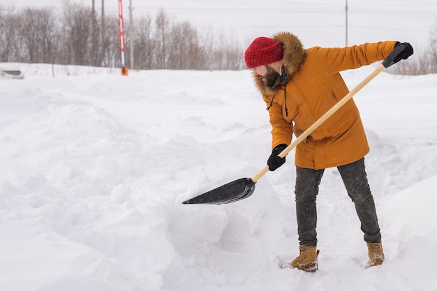 Man cleaning snow from sidewalk and using snow shovel winter season