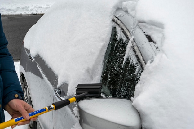 Man cleaning snow off his car during winter snowfall