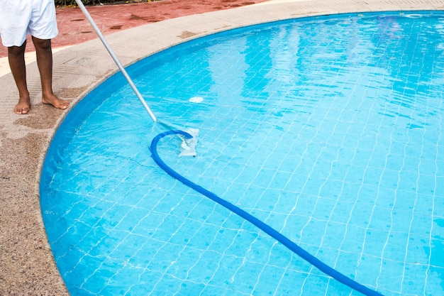 Man cleaning a swimming pool in summer. Cleaner of the swimming pool 