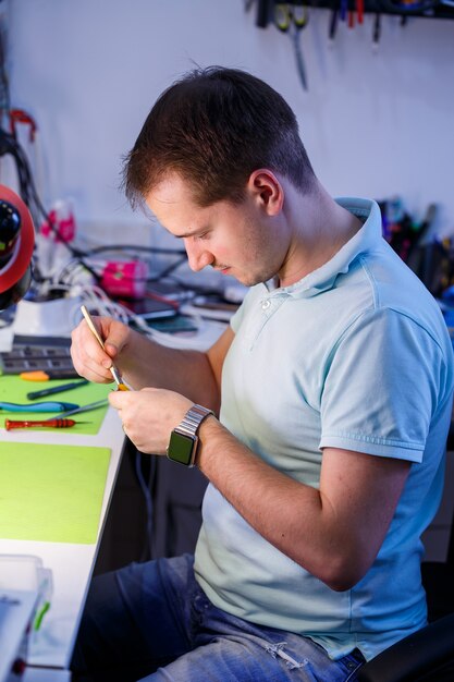 Man cleans a laptop with a special tool from dust. Repair and maintenance of laptops and PCs Advertising services for the repair of electronics and devices.