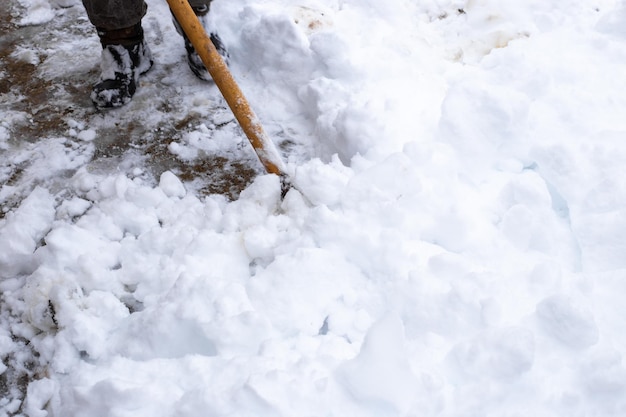 A man cleans the snow in the yard with a shovel Winter snowdrifts