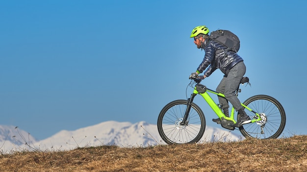 Man climbing a mountain meadow with mountain bike