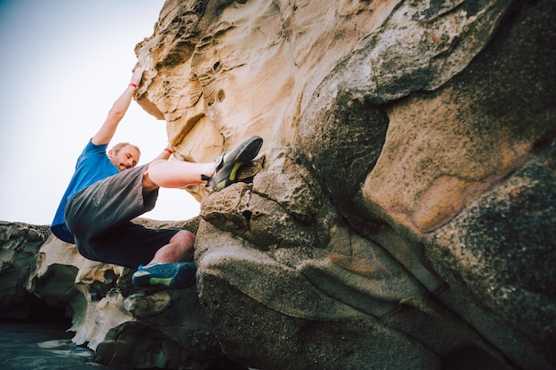 Photo man climbing on rock formation against sky