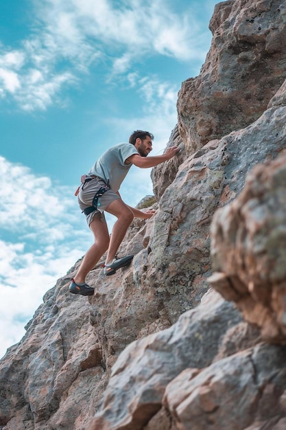 Photo a man climbing up the side of a mountain