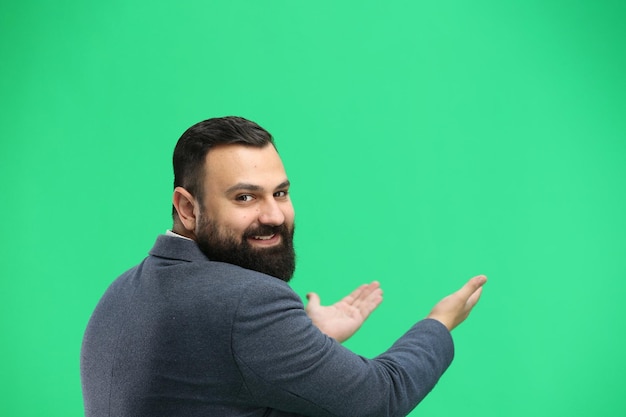 A man closeup on a green background points forward