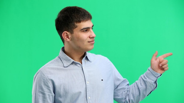 Photo a man closeup on a green background points to the side