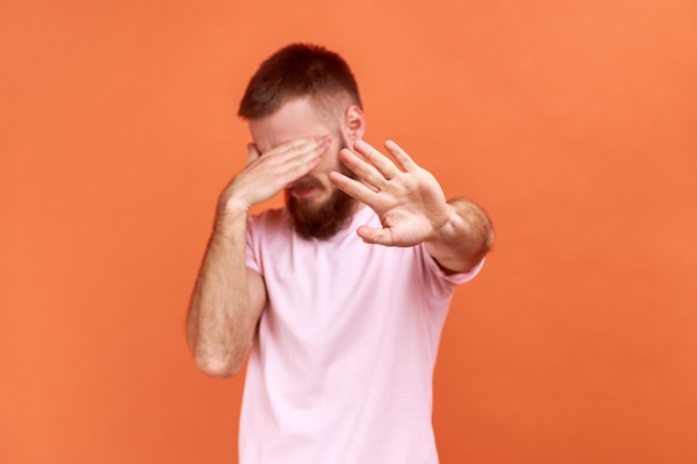 Man closing eyes with palm of hand stretching out another hand forward touching space