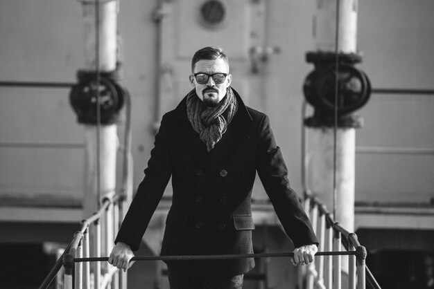 Man in a coat with a scarf poses on the street