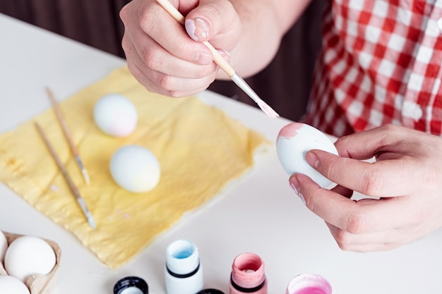 Man coloring easter eggs at home kitchen