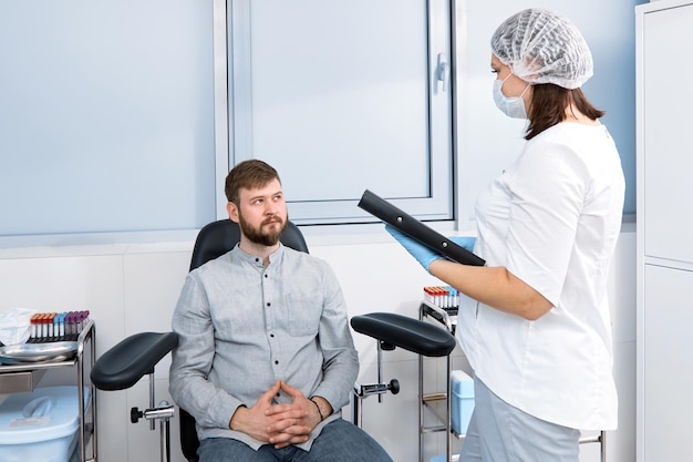 A man communicates with nurse sitting in chair in treatment room